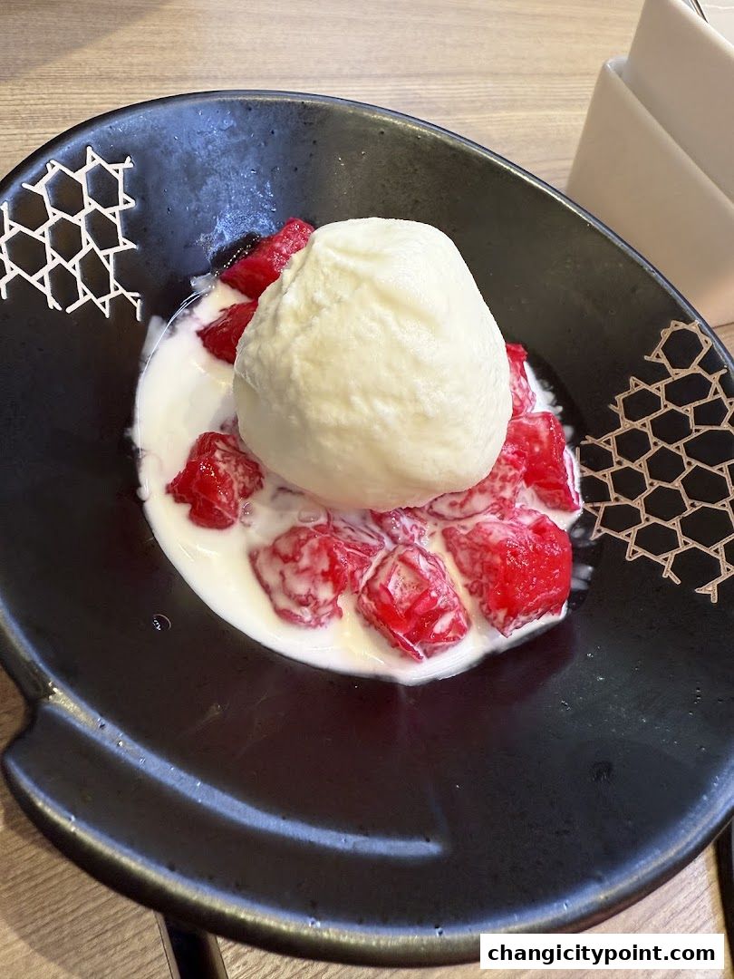 A black bowl filled with red cubes and a scoop of ice cream in coconut milk.