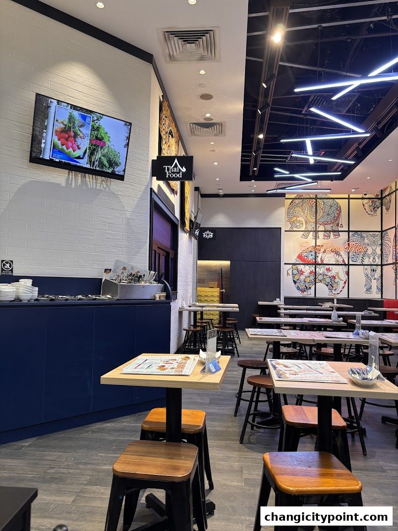 Interior view of a Thai food restaurant with tables, chairs, and decorative wall art.