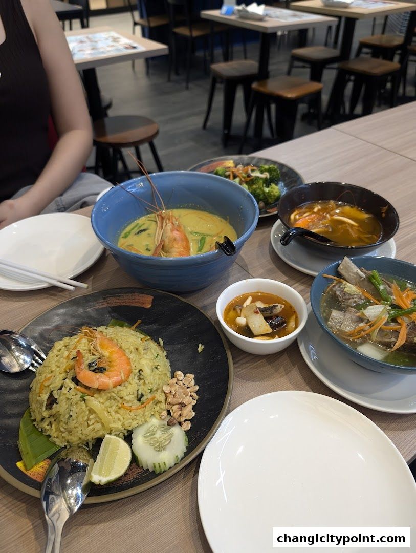 A table laden with various Thai dishes, including fried rice, soup, and a curry.