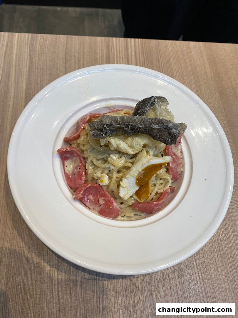 A close-up of a creamy pasta dish with sausage, egg, and crispy fish skin.