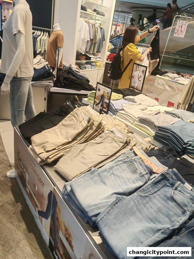 A display of folded pants and shirts in a Giordano clothing store.