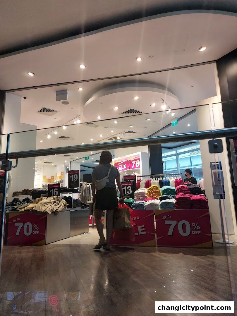 A woman walks into a Giordano store with sale signs advertising up to 70% off.
