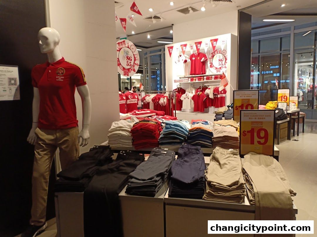 Mannequin in Giordano store displays red polo shirt and folded pants, with sale signs.