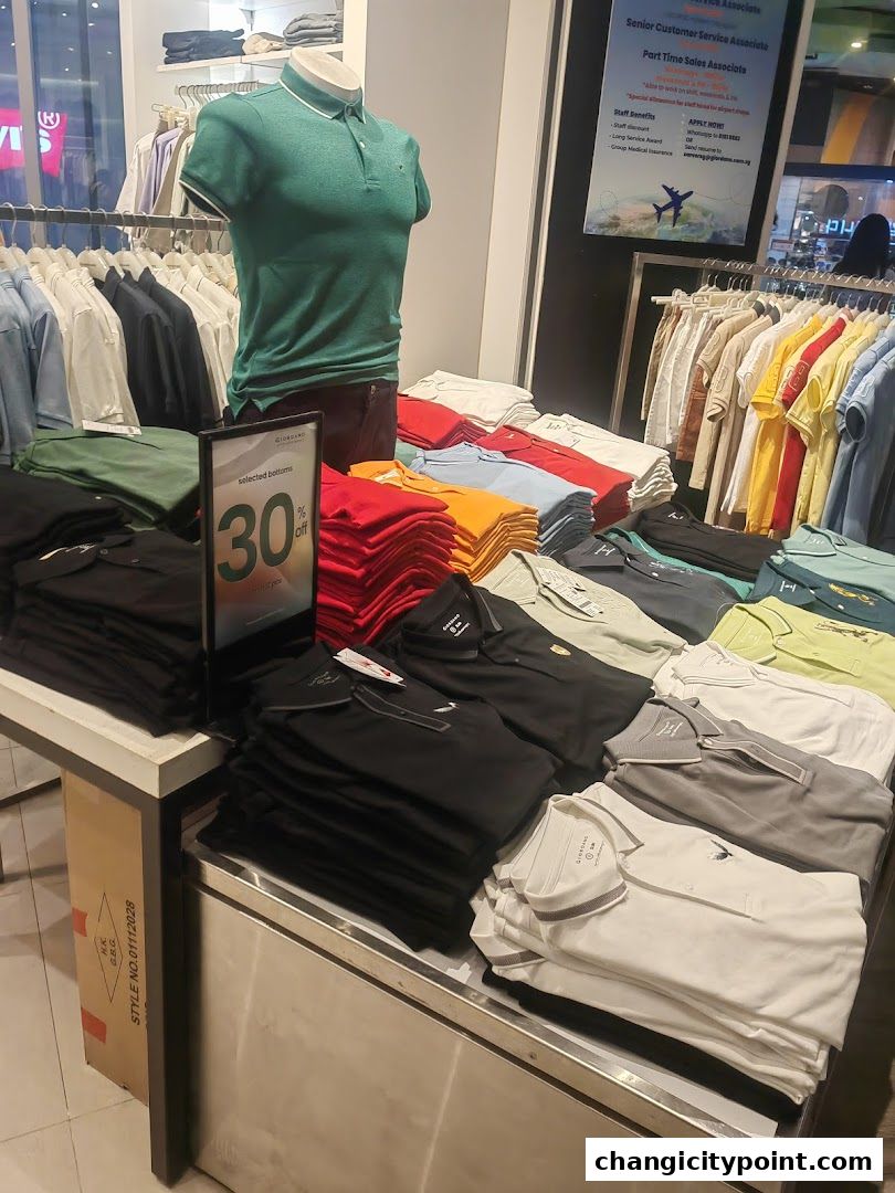 A display of folded polo shirts in various colors and a mannequin wearing a green polo shirt.
