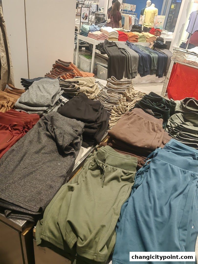A display of folded casual pants in various colors and styles.