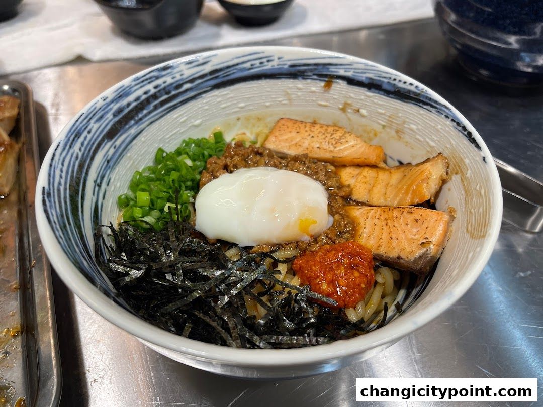 A bowl of ramen with salmon, egg, seaweed, and green onions.
