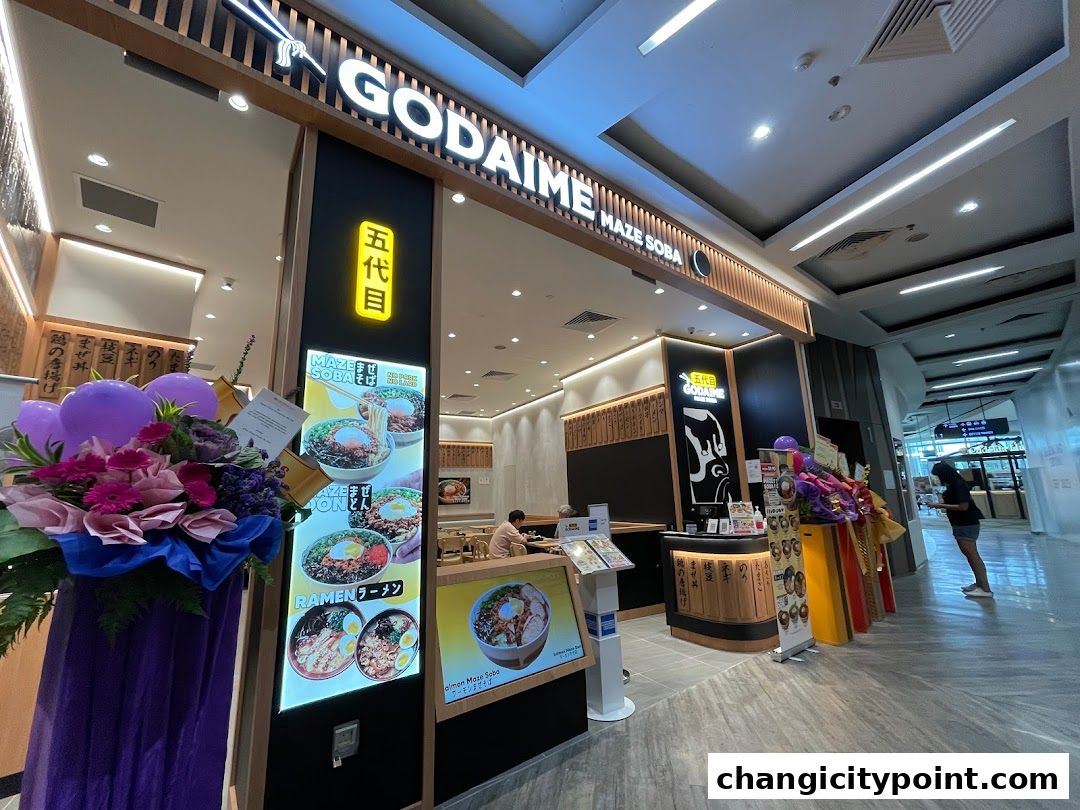 The exterior of Godaime Maze Soba restaurant with illuminated signage and food displays.