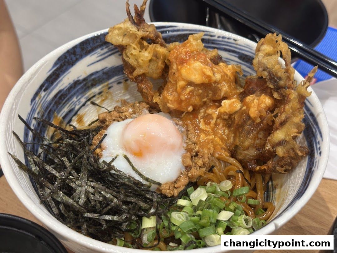 A close-up of a delicious bowl of noodles topped with soft-shell crab and a poached egg.