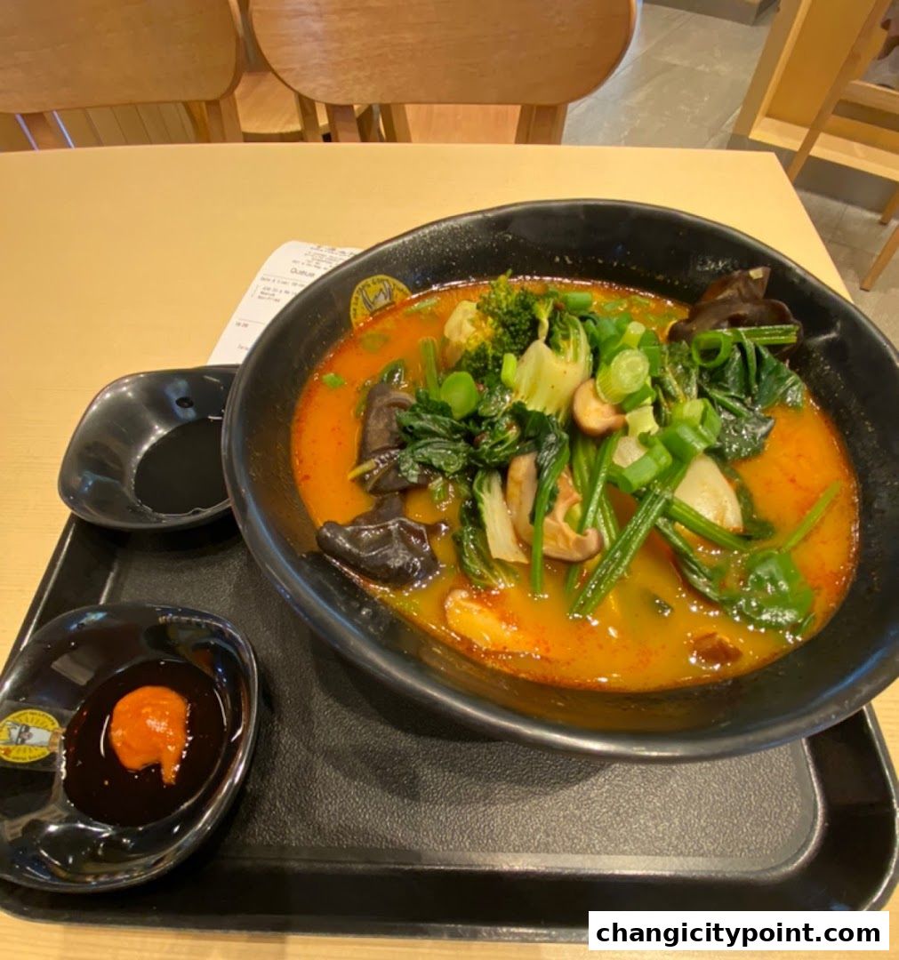 A steaming bowl of Mala Tang with fresh vegetables and mushrooms, served with dipping sauces.