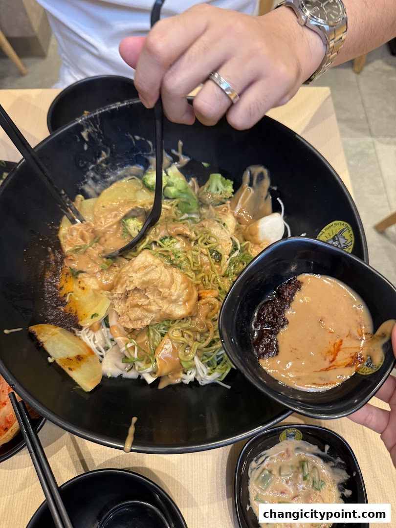 A close-up of a large bowl of Mala Tang with various ingredients and dipping sauces.