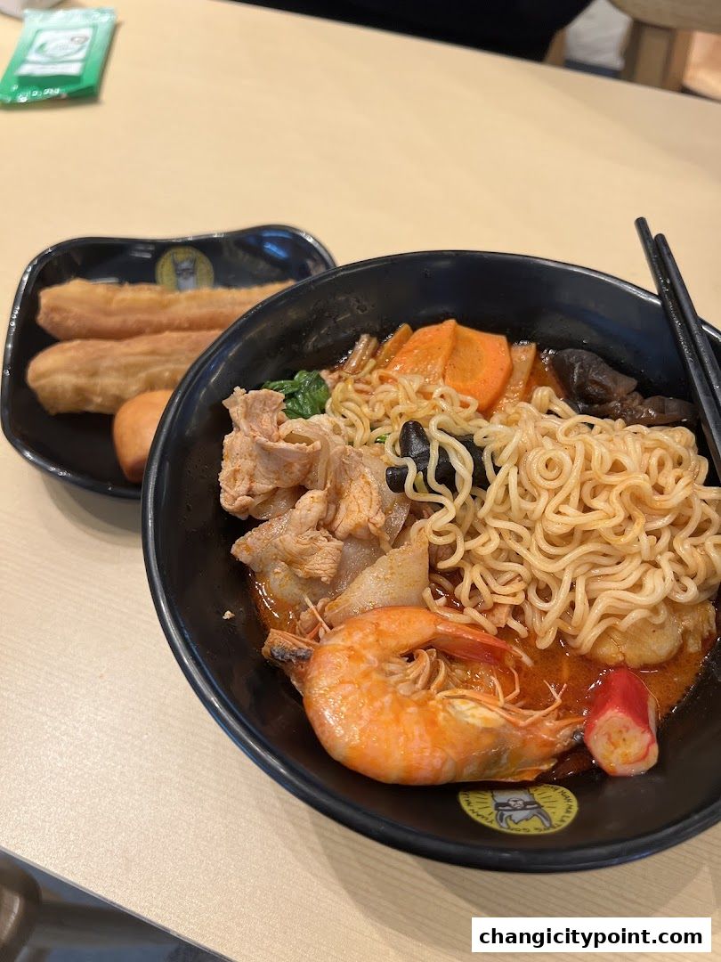 A bowl of Mala Tang with noodles, shrimp, meat, and vegetables, served with fried dough sticks.