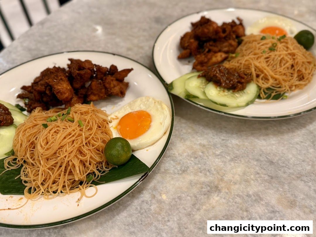 Two plates of delicious Nasi Lemak with fried chicken, noodles, egg, and cucumber.