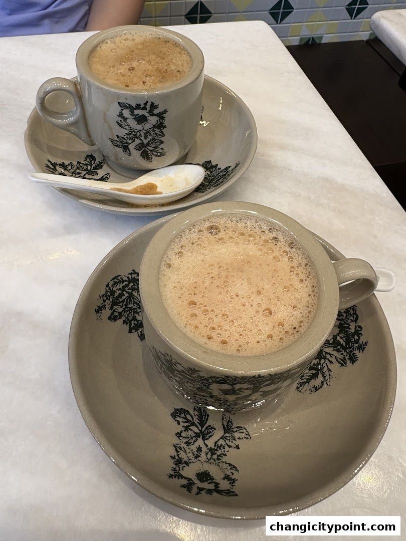 Two cups of frothy coffee served in vintage ceramic mugs with floral designs.