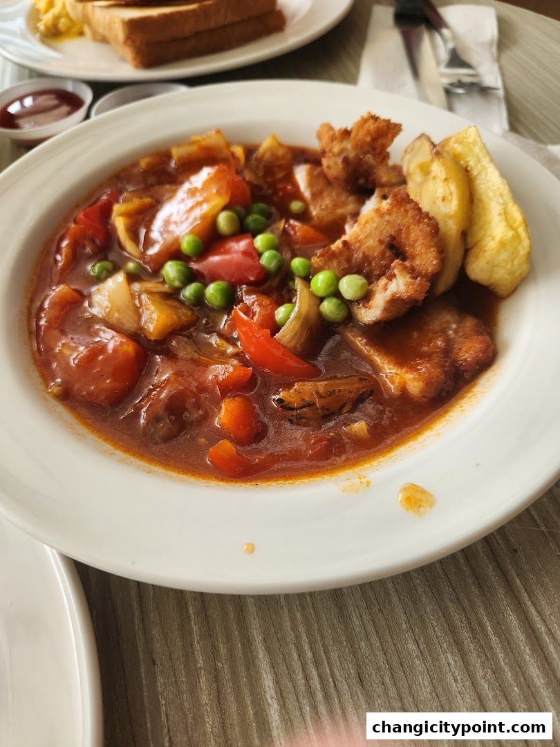 A close-up of a hearty meal with stewed vegetables, meat, and fries.