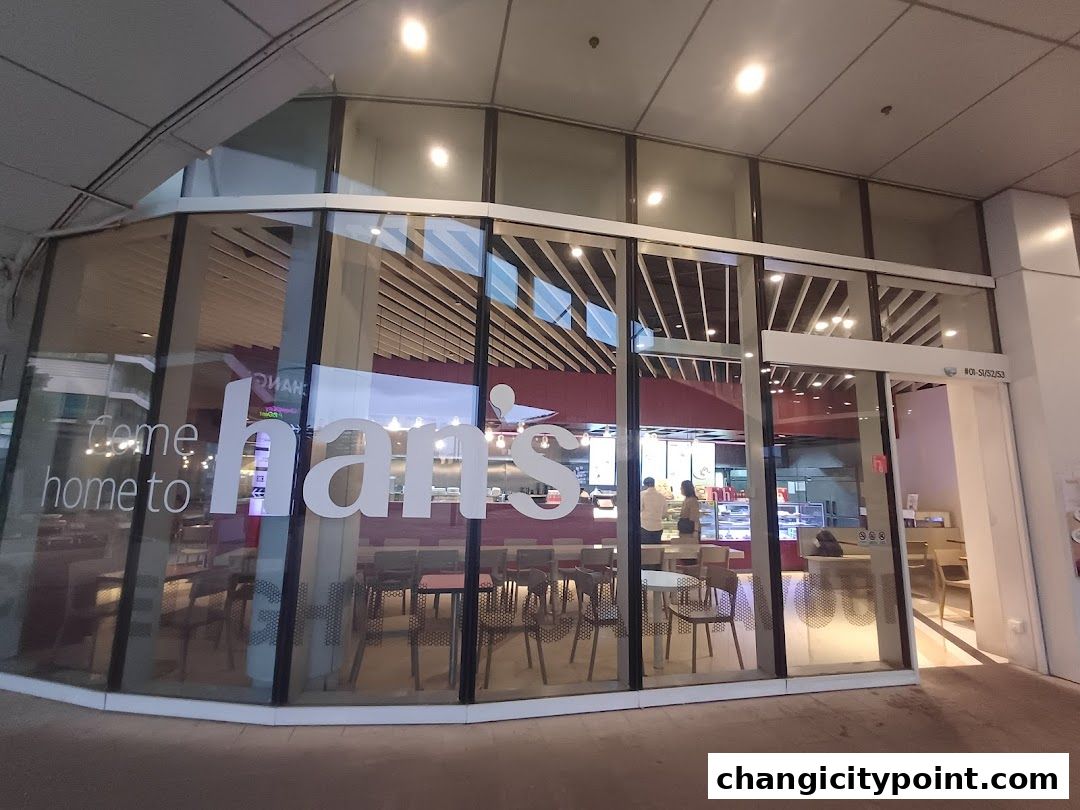 Exterior view of Hans Cafe Changi City Point with large glass windows and interior seating visible.