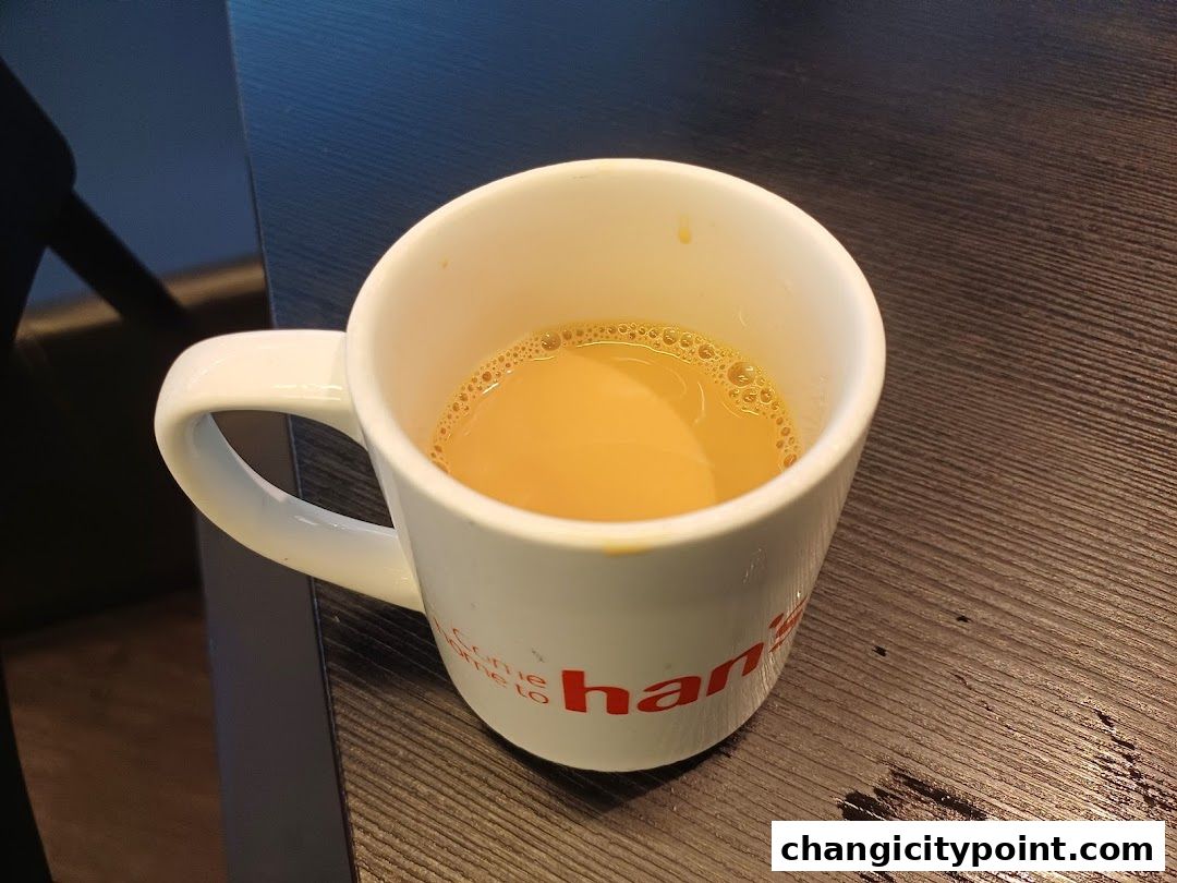 A white mug filled with a light brown beverage, likely coffee or tea.
