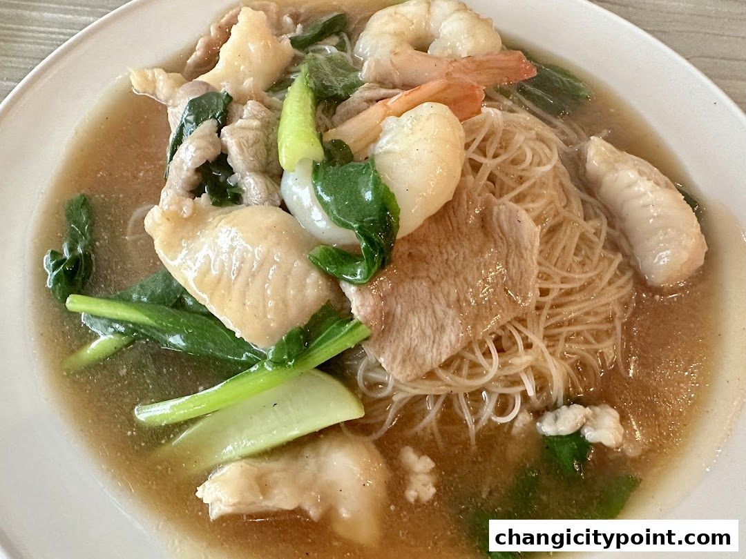 A close-up shot of a delicious noodle dish with seafood, meat, and vegetables.