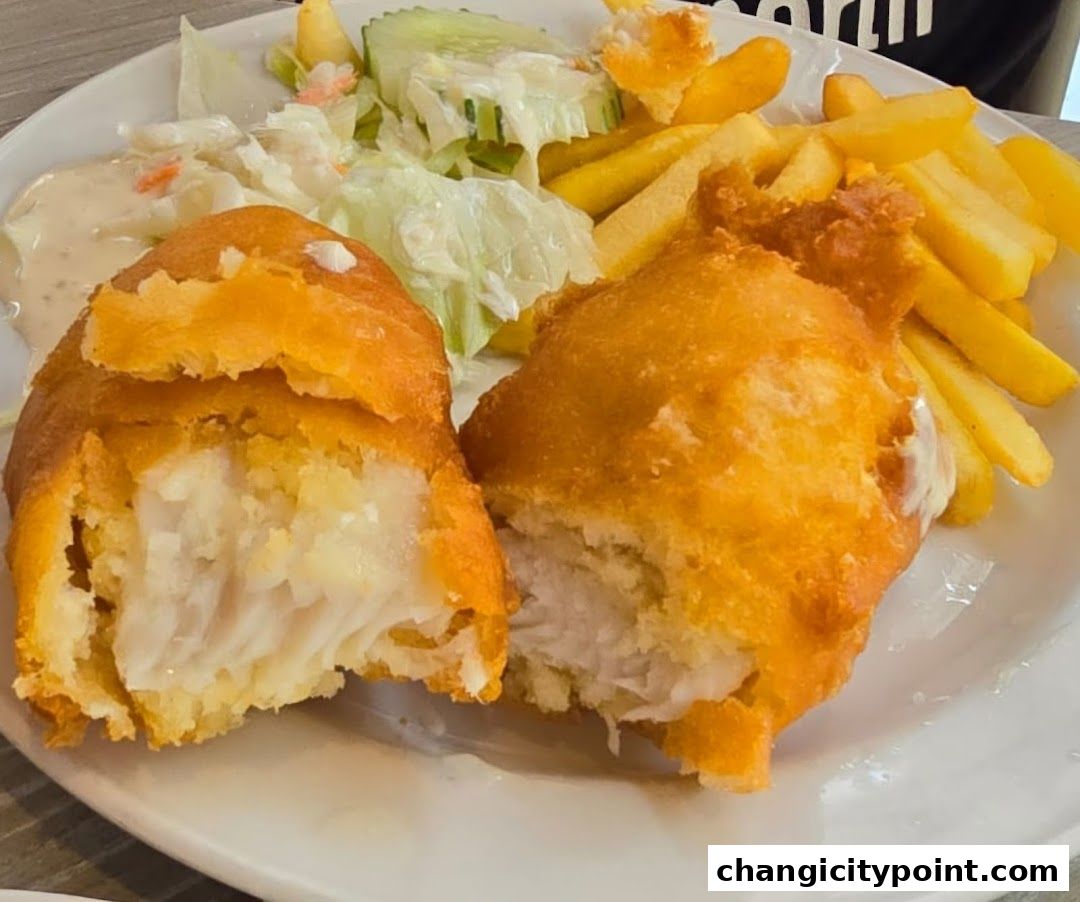 A plate of fish and chips with coleslaw and tartar sauce.