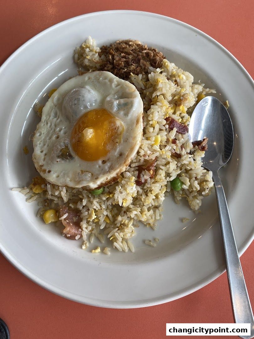 A plate of fried rice with a sunny-side-up egg and crispy toppings.