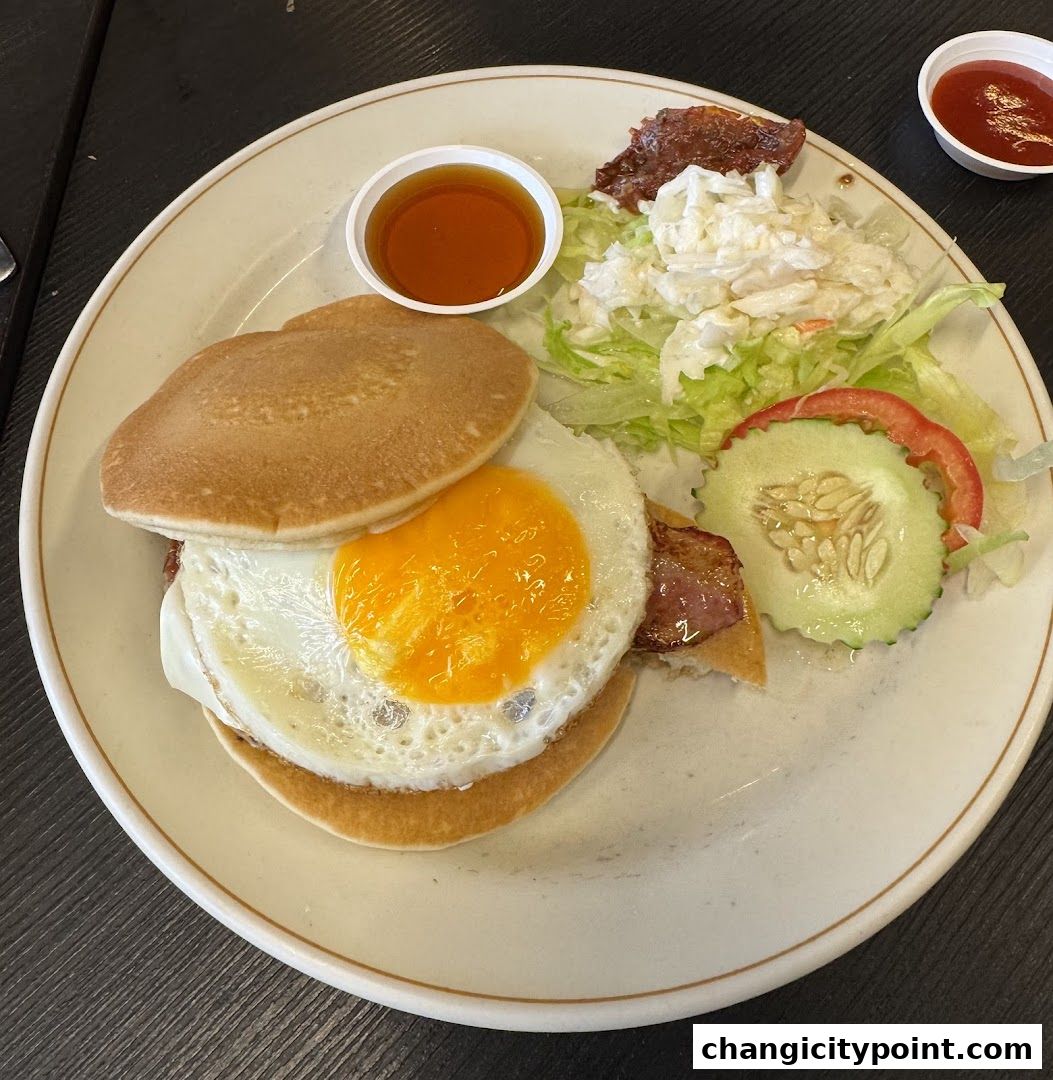 A hearty breakfast plate with pancakes, fried egg, bacon, salad, and syrup.