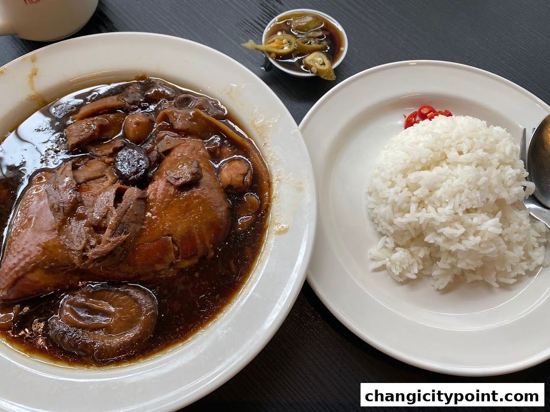 A plate of braised chicken with mushrooms and a side of white rice.