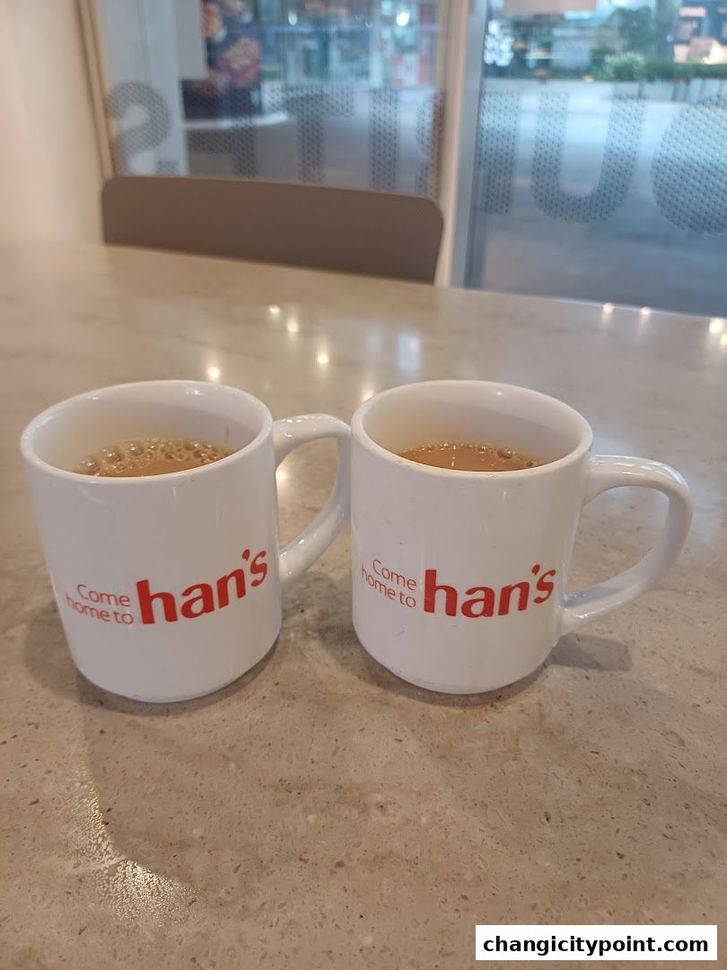 Two white mugs with 'Come home to han's' logo filled with coffee.