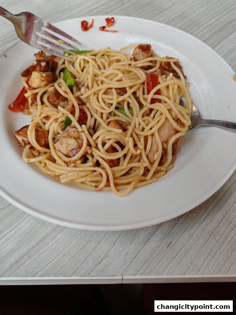 A plate of spaghetti with chicken and vegetables, served with forks.