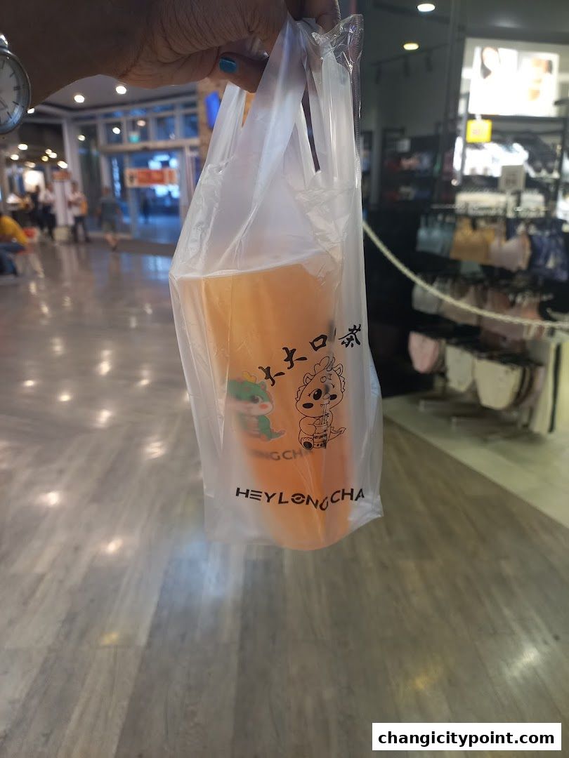 A person holds a plastic bag with a beverage from Hey Long Cha.