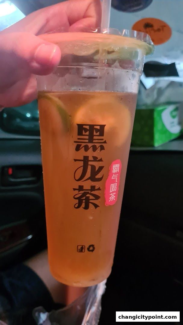 A hand holds a refreshing cup of iced tea with lemon slices and Chinese characters.