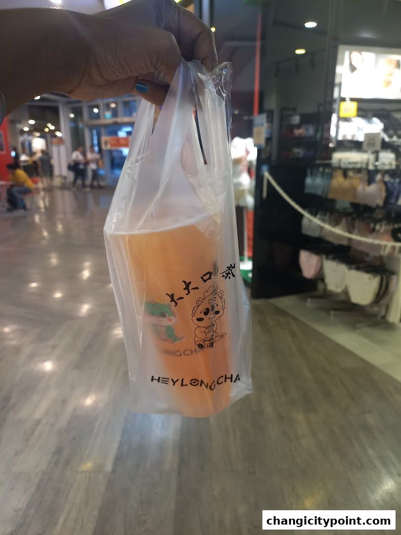 A hand holds a plastic bag with a beverage from Hey Long Cha.