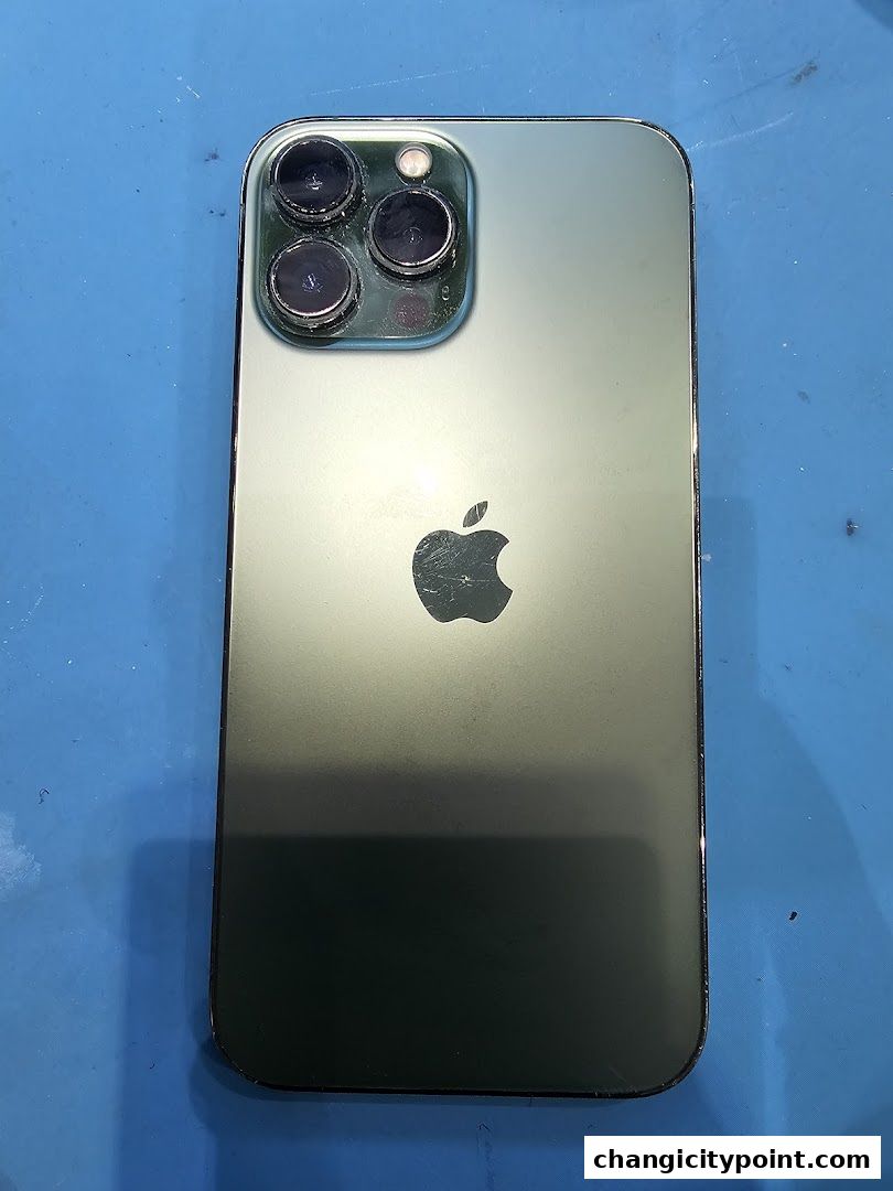 A close-up shot of the back of a green iPhone with a triple-lens camera system.