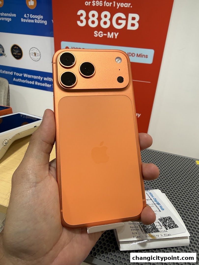 A hand holds an orange smartphone with a triple camera setup, showcasing a promotional offer.