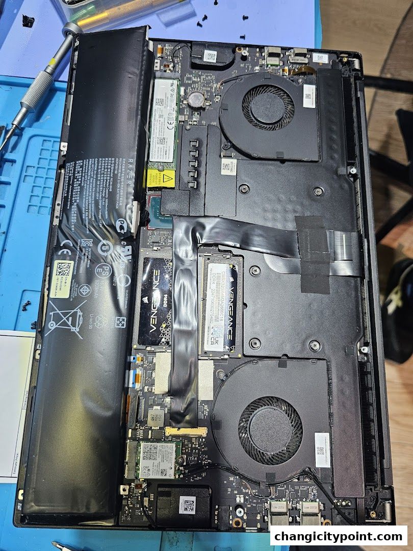 Internal components of a disassembled laptop, including battery, fans, and motherboard.