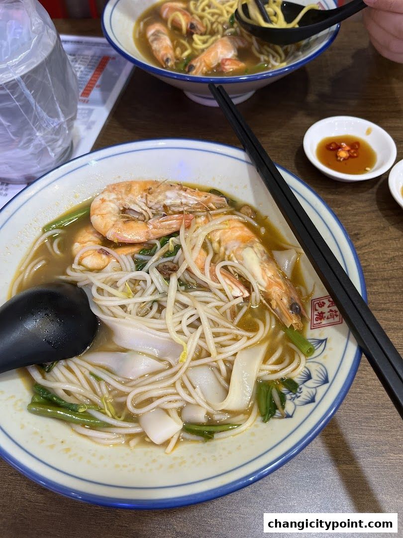 Two bowls of prawn noodle soup with fresh prawns and noodles.