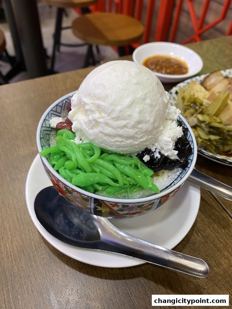 A refreshing bowl of dessert with ice cream, green jelly, and red beans.