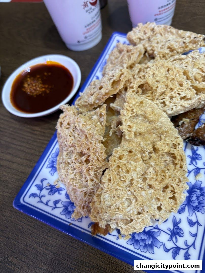 Crispy fried food served with a side of chili sauce on a blue and white plate.
