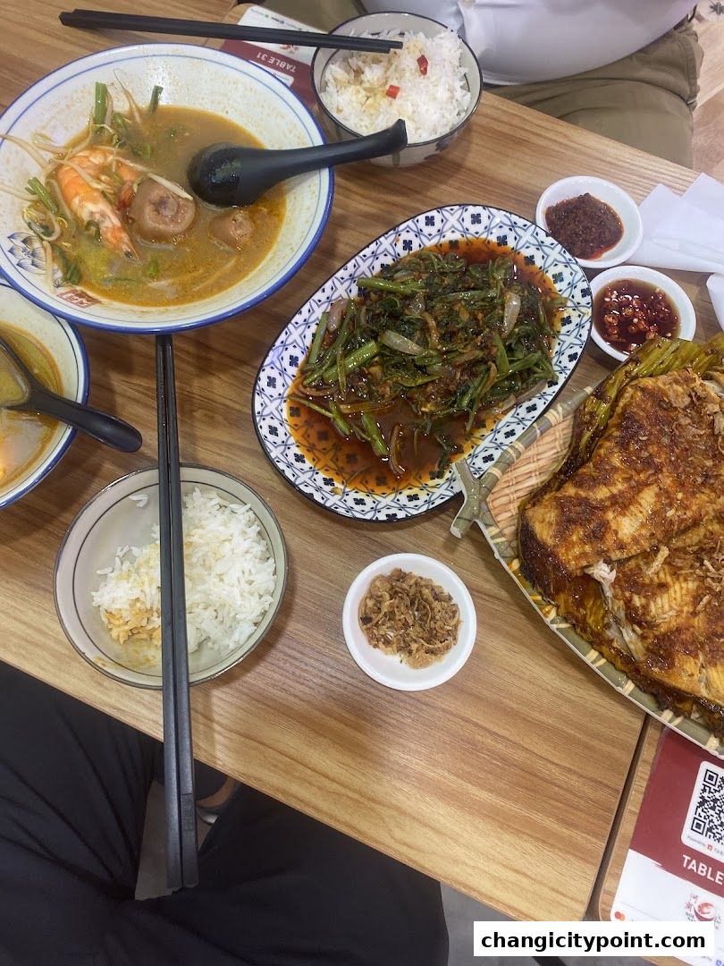 A table laden with delicious Southeast Asian dishes, including prawn noodles, stir-fried vegetables, and grilled fish.