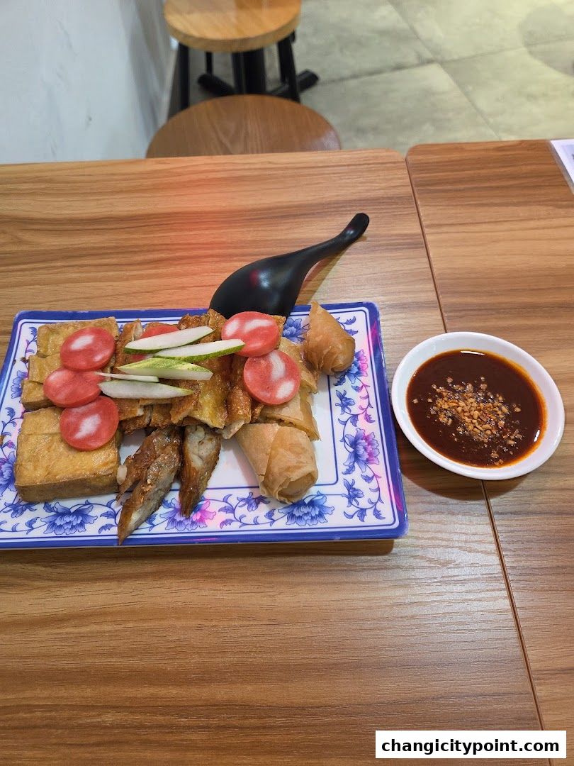 A plate of fried snacks with dipping sauce and a spoon on a wooden table.