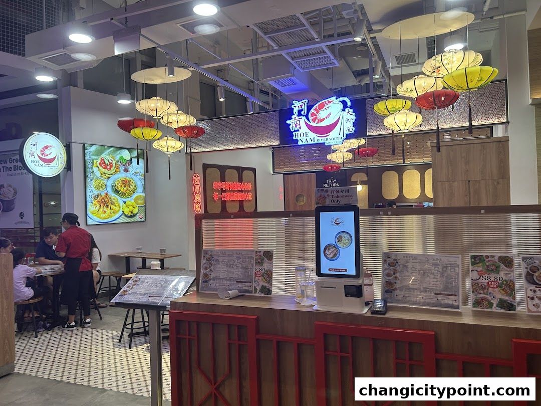 Interior of a restaurant with seating, a digital ordering kiosk, and decorative lanterns.