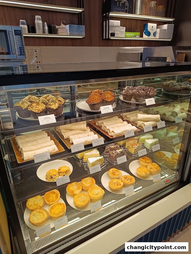 A display case filled with various pastries, cakes, wraps, and pies at Huggs Coffee.