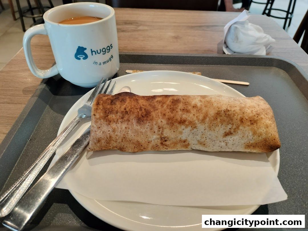 A mug of coffee and a rolled pastry on a tray at Huggs Coffee.