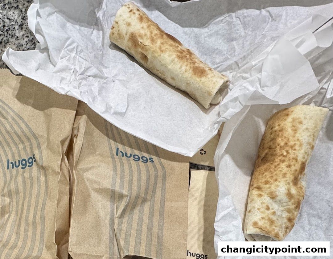 Two golden-brown wraps are presented on white paper, with Huggs Coffee branded bags nearby.