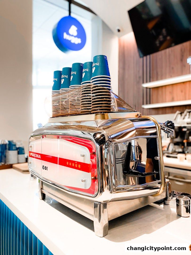 A professional espresso machine with stacked coffee cups at Huggs Coffee.
