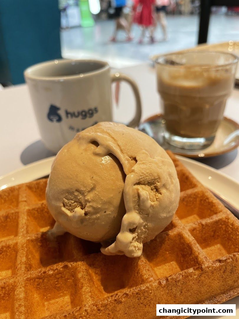 A waffle topped with ice cream and a cup of coffee from Huggs Coffee.