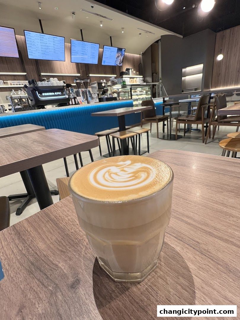 A close-up of a latte with art on a wooden table inside Huggs Coffee.