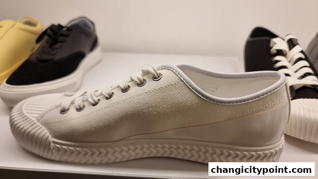Close-up view of white canvas sneakers with rubber soles, displayed in a shop.