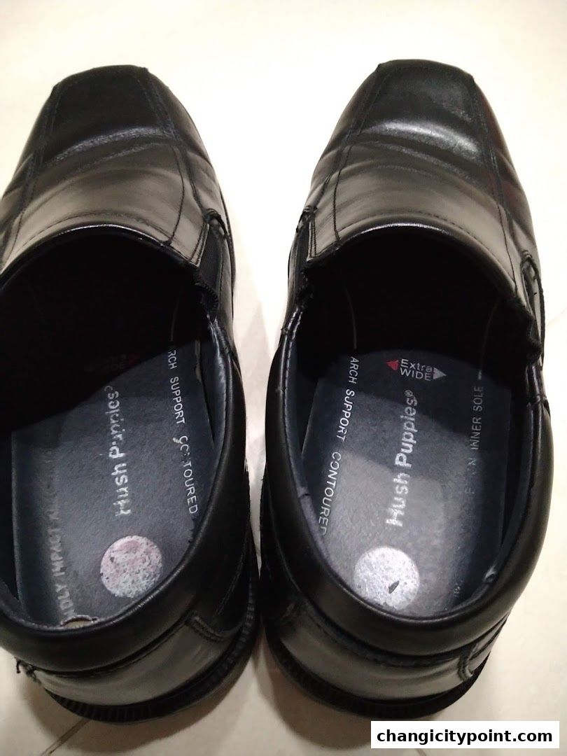 A pair of black Hush Puppies leather slip-on shoes with supportive insoles.