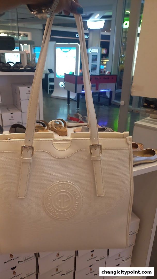 A white Hush Puppies tote bag is displayed in front of shoes and shoe boxes.