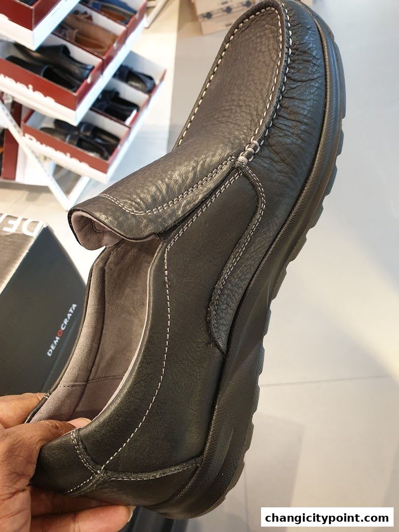 A close-up shot of a dark leather slip-on shoe with white stitching.