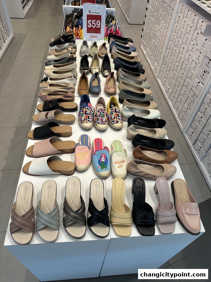 A wide selection of Hush Puppies shoes displayed on shelves and tables in a retail store.